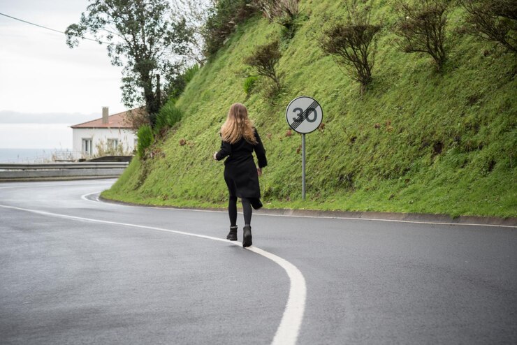 Foto vista traseira em todo o comprimento de uma mulher caminhando na estrada