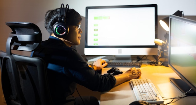 Vista traseira Feliz jogador masculino asiático profissional jogando videogame no computador pessoal Esport jogo online