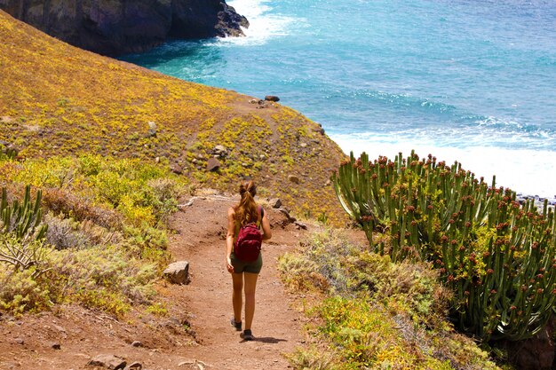 Vista traseira jovem alpinista caminhando em direção ao mar em macizo de anaga em tenerife