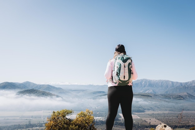 Vista traseira jovem latina com mochila, no topo de uma colina