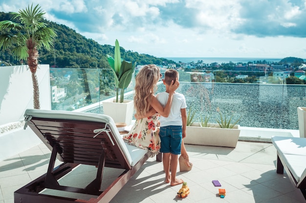 Foto vista traseira: mãe e filho estão olhando para a vista da varanda de seu hotel.