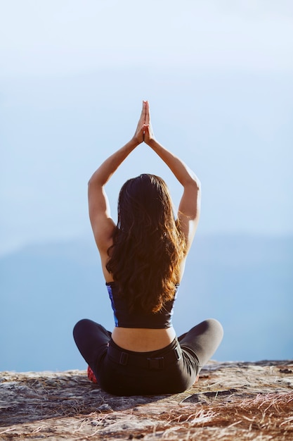 vista traseira mulher asiática fazendo ioga na montanha