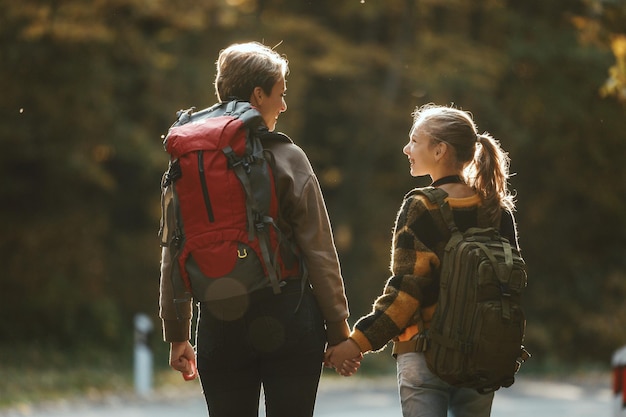 Vista trasera de una adolescente y su madre caminando juntas por el bosque en otoño.