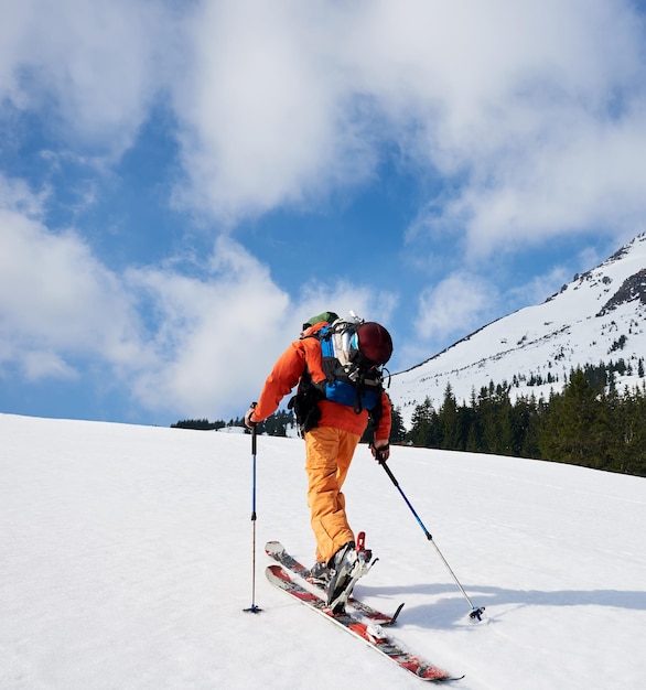 Foto vista trasera del alpinista de esquí caminando a lo largo de la cresta nevada con t