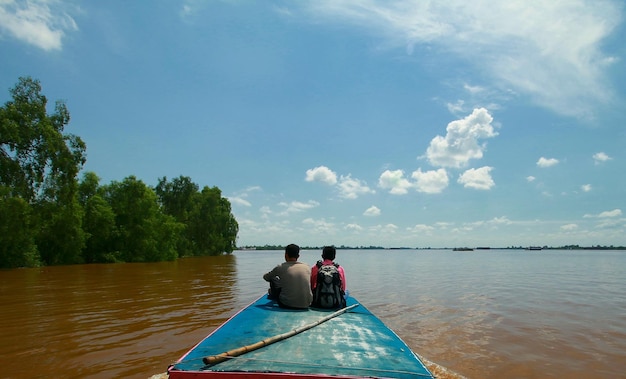 Vista trasera de amigos navegando en barco en el río contra el cielo