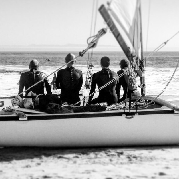 Foto vista trasera de amigos sentados en un barco en la playa