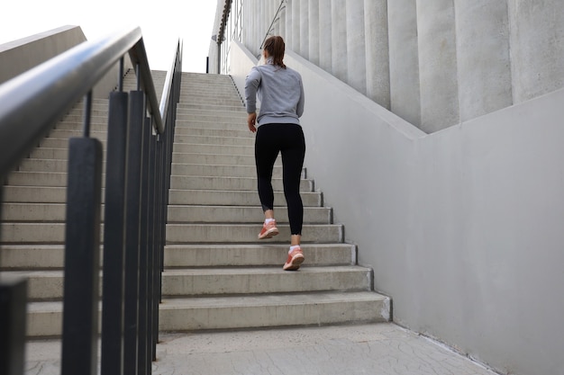 Vista trasera del atleta corredor corriendo en las escaleras. La aptitud de la mujer está haciendo jogging al aire libre.