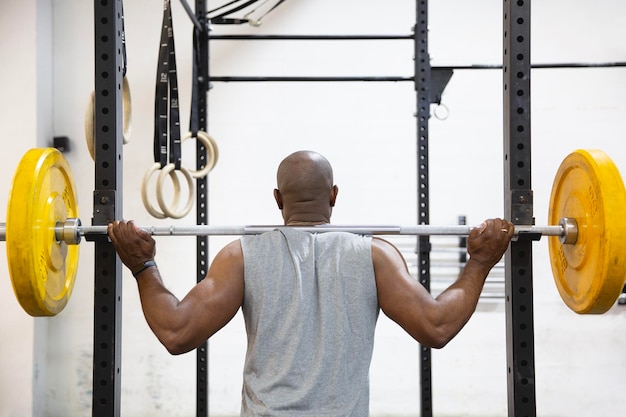 Foto vista trasera del atleta masculino afroamericano haciendo ejercicio con pesas