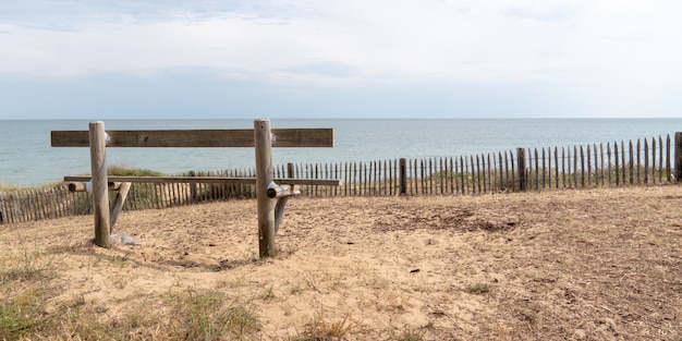 Vista trasera del banco de madera vacía en la costa atlántica en Jard sur Mer Vendee Francia en web banner template banner