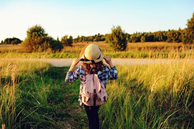 Foto vista trasera de una chica con sombrero de pie en el campo contra el cielo