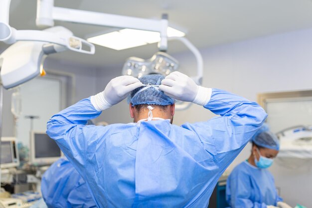 Vista trasera del cirujano masculino con mascarilla quirúrgica en el quirófano del hospital