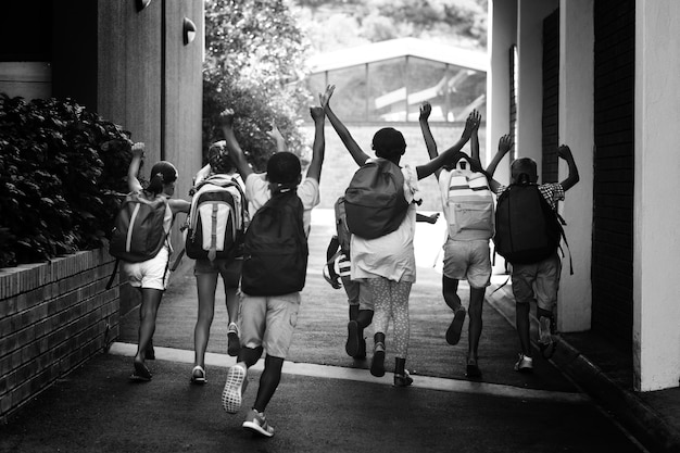 Foto vista trasera de compañeros corriendo en el campus de la escuela