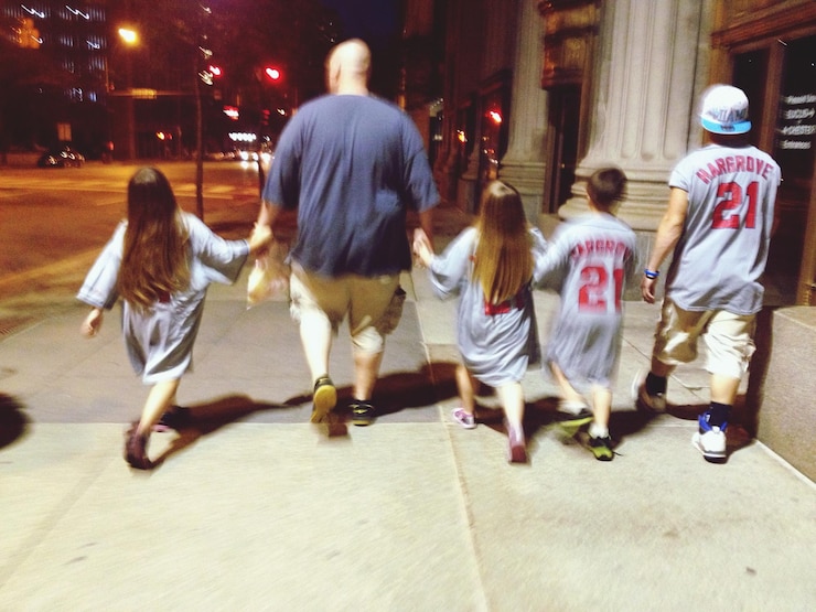 Foto vista trasera completa de la familia caminando por la calle por la noche