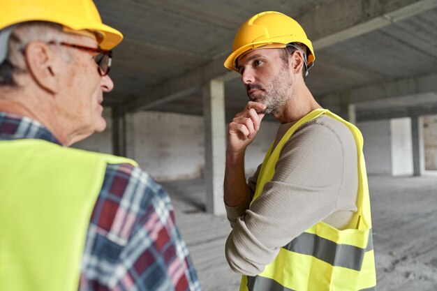 Vista trasera de dos ingenieros caucásicos discutiendo en el sitio de construcción