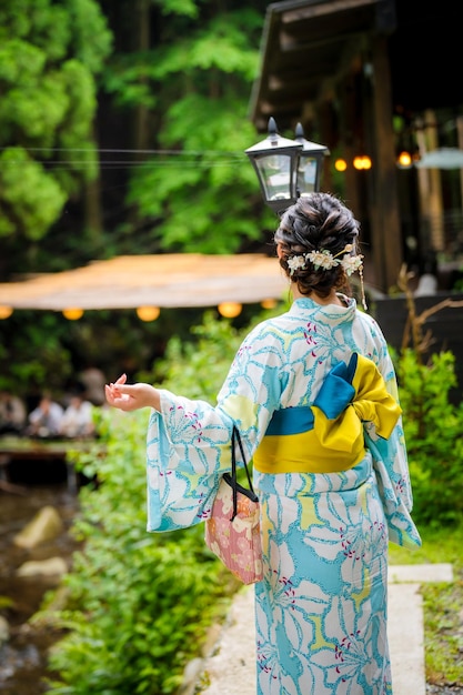 Vista trasera de dos mujeres con kimono de verano yukata japonés caminando por la carretera en la naturaleza