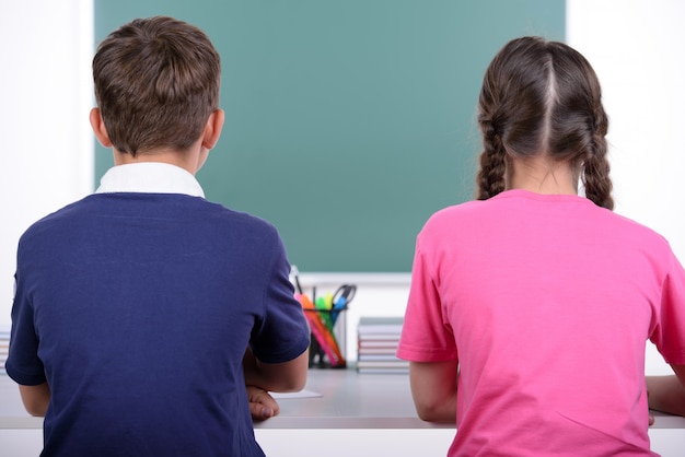 Vista trasera de dos pequeños compañeros leyendo un libro juntos.