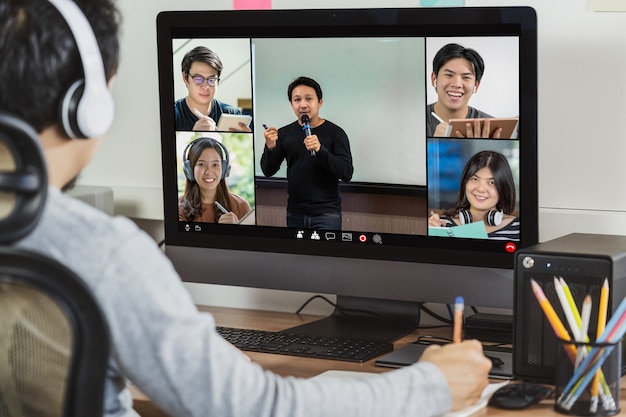 Vista trasera del empresario asiático trabajando y reunión en línea a través de videoconferencia con colega