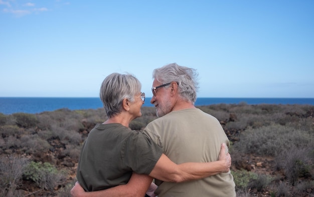 Vista trasera de una encantadora pareja de ancianos sentada abrazándose y mirándose a los ojos