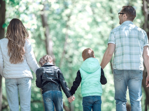 Vista trasera de la familia con dos niños caminando de la mano en el parque