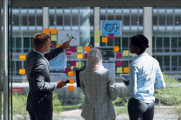 Foto vista trasera de gente de negocios discutiendo sobre notas adhesivas en la oficina. una empresa moderna pone en marcha un nuevo concepto de negocio con un empresario trabajando duro