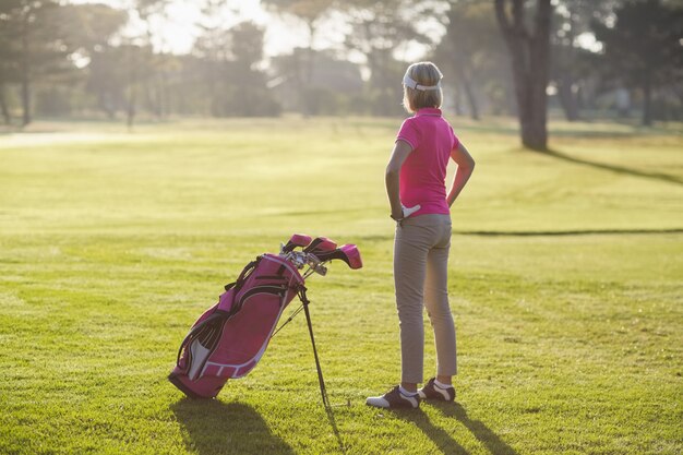 Vista trasera del golfista maduro con las manos en la cadera