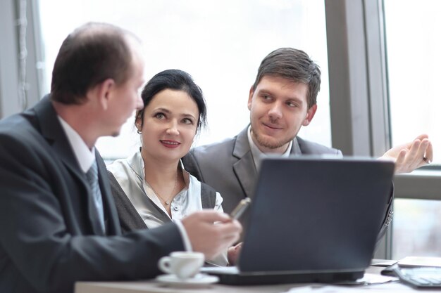 Vista trasera del grupo de gente de negocios usando una laptop en la oficina