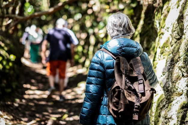 Vista trasera de un grupo de personas mayores activas caminando en el bosque, una anciana caucásica sosteniendo una mochila disfrutando de un estilo de vida saludable y la naturaleza