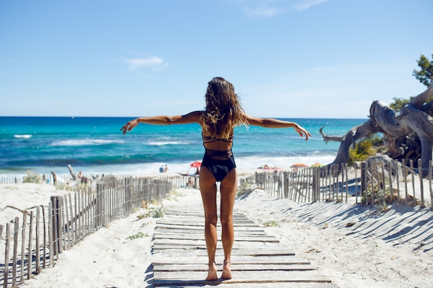 Vista trasera de una hermosa joven posando en la playa. Océano, playa, arena, fondo del cielo. Vacaciones en la isla de Córcega, Francia.