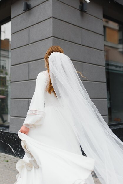 Vista trasera. Una hermosa joven con un vestido de novia blanco.