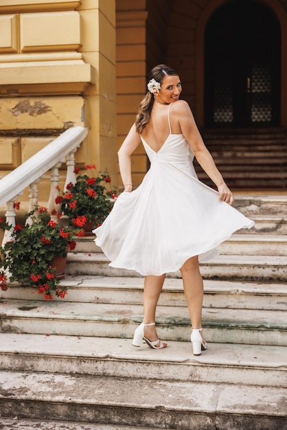 Vista trasera de una hermosa novia con un hermoso vestido de novia blanco divirtiéndose y bailando al aire libre el día de su boda.