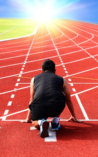 Foto vista trasera de un hombre arrodillado en la pista de atletismo