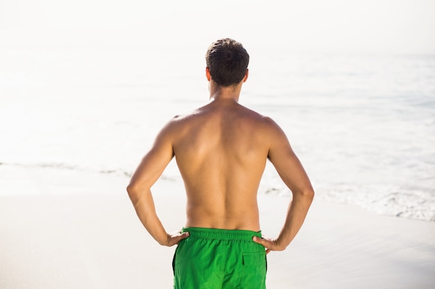 Vista trasera del hombre en bañador de pie en la playa