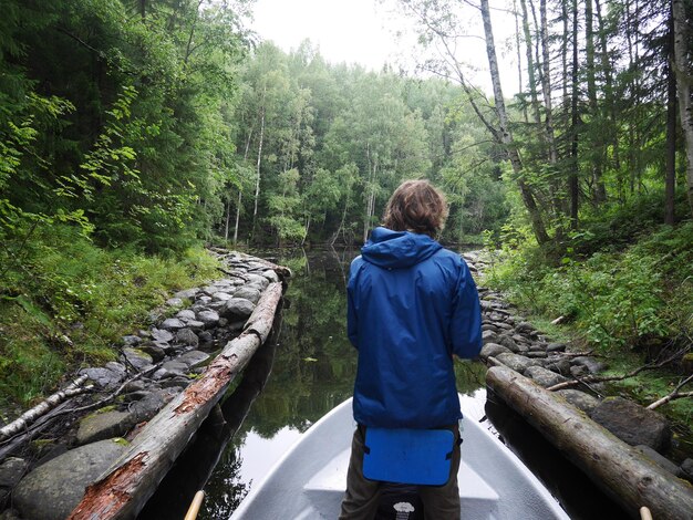 Foto vista trasera de un hombre en un barco en un lago en el bosque