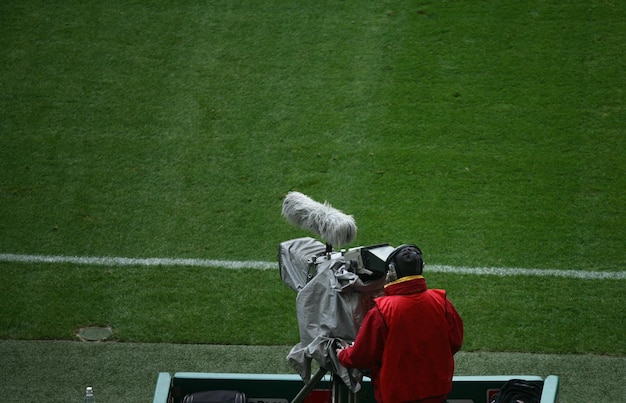 Foto vista trasera de un hombre con una cámara de televisión en un campo deportivo