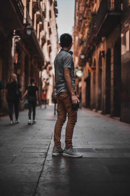 Vista trasera de un hombre caminando por la calle en medio de edificios