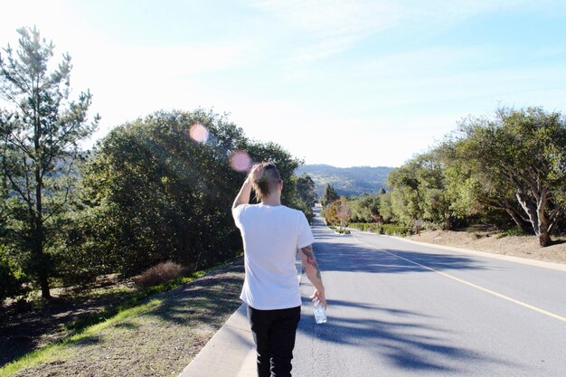 Foto vista trasera de un hombre caminando por la carretera contra el cielo