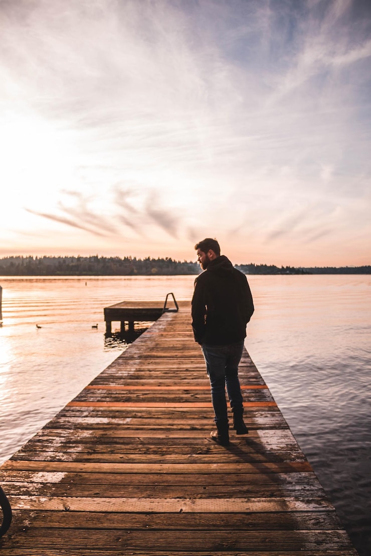 Foto vista trasera de un hombre caminando por el muelle sobre el lago contra el cielo