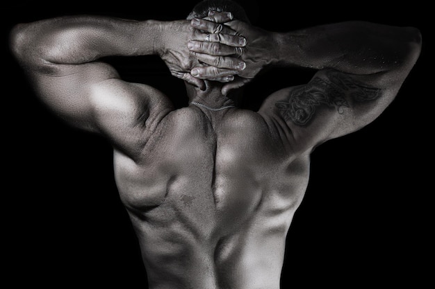 Foto vista trasera de un hombre sin camisa flexionando los músculos contra un fondo negro