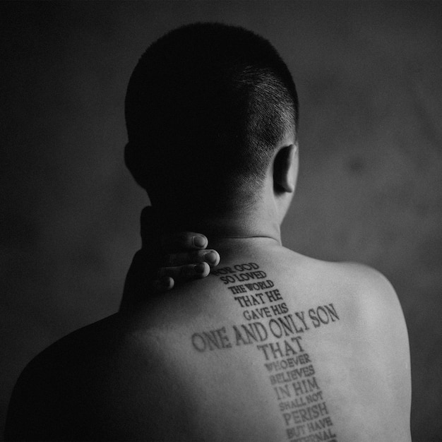 Vista trasera de un hombre sin camisa con tatuaje en la espalda