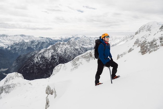 Vista trasera de un hombre esquiando en una montaña nevada contra el cielo