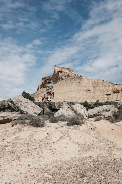 Vista trasera del hombre en una excursión para descubrir tierras salvajes en vacaciones hombre con pasión por los viajes de pie en un paisaje rocoso