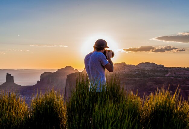 Vista trasera de un hombre fotografiando durante la puesta de sol