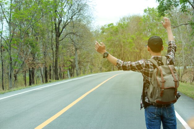 Foto vista trasera de un hombre haciendo autostop en la carretera en el bosque