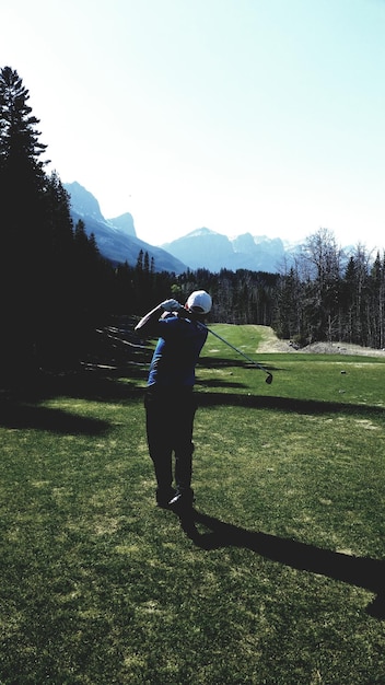 Foto vista trasera de un hombre jugando al golf en el campo contra un cielo despejado