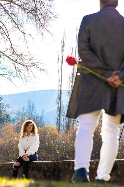 Vista trasera de un hombre latino enamorado escondiendo una rosa para su novia Concepto de una rosa para la novia Día de San Valentín