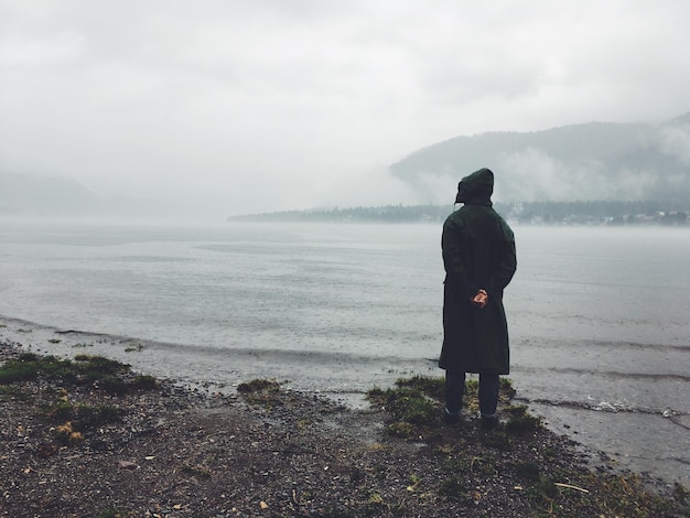 Foto vista trasera de un hombre mirando al mar contra el cielo