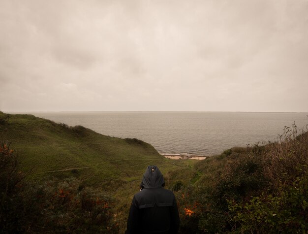 Foto vista trasera de un hombre mirando al mar contra el cielo