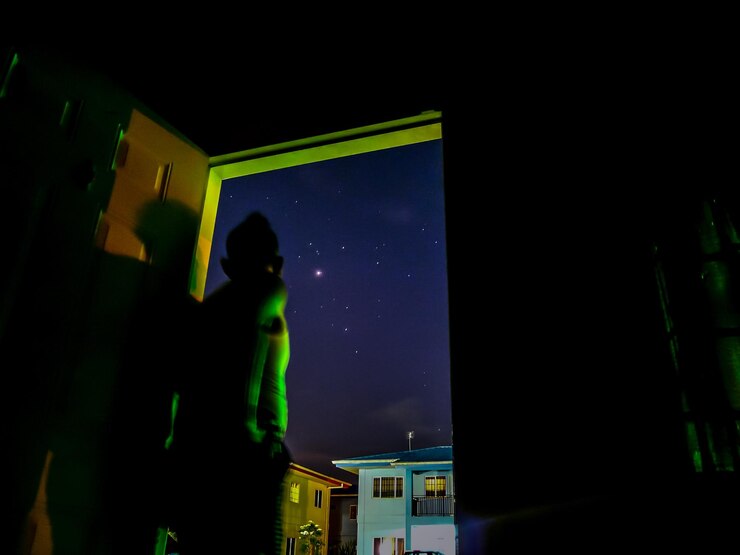 Foto vista trasera de un hombre mirando el campo de estrellas mientras está de pie en la puerta por la noche