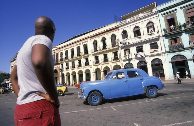 Vista trasera del hombre mirando el coche vintage azul en la calle