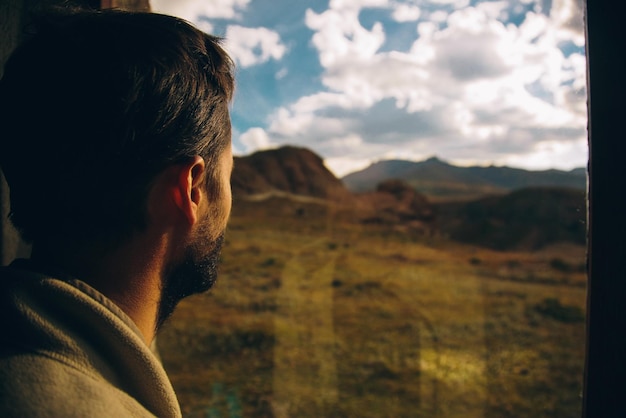 Foto vista trasera de un hombre mirando las montañas contra un cielo nublado